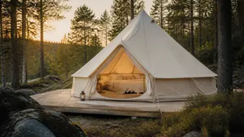 Kremfarget glampingtelt i bomull på en treplatting i skogen